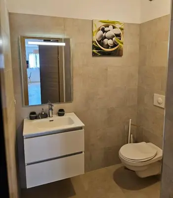 a bathroom with a sink and a toilet and a mirror at Appartement moderne à Lucciana avec terrasse ensoleillée. in Lucciana