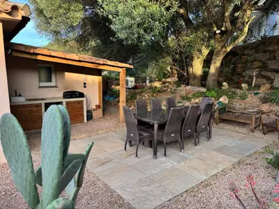a patio with a table and chairs and a cactus at A l'Ombra Di l'Alivu in Figari