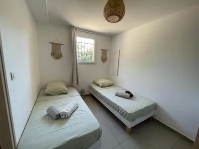 two twin beds in a room with a window at A l'Ombra Di l'Alivu in Figari