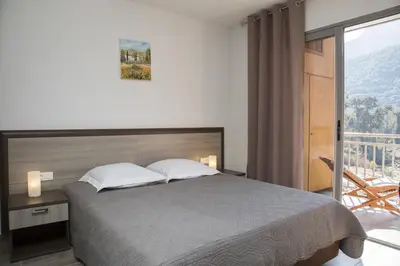 a bedroom with a large bed and a balcony at Résidence Hotelière Capu Seninu in Porto Ota