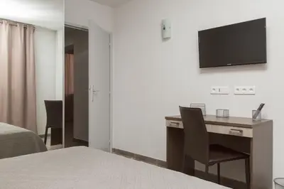 a bedroom with a desk and a television on the wall at Résidence Hotelière Capu Seninu in Porto Ota