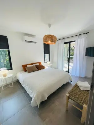 a white bedroom with a large bed and a chandelier at Villa La Vesta Porto Vecchio in Porto-Vecchio