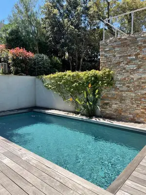 a swimming pool in a yard with a wooden deck at Villa La Vesta Porto Vecchio in Porto-Vecchio
