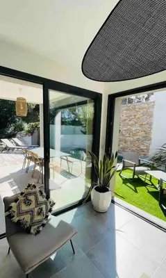 a living room with glass doors and a chair at Villa La Vesta Porto Vecchio in Porto-Vecchio