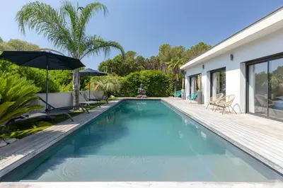 a swimming pool with an umbrella next to a house at Villa 