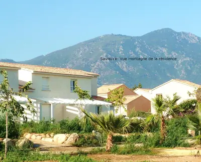 a white house with a mountain in the background at Villa bord de mer,3 chambres, piscine chauffée, climatisée in Cervione