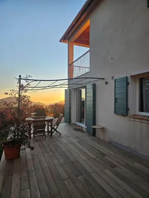 a wooden deck with a table and a dining table on a house at Quenza-Alta Rocca in Quenza
