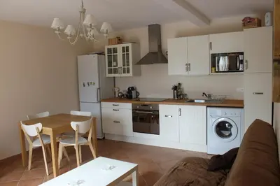 a kitchen with white cabinets and a table and a dining room at Quenza-Alta Rocca in Quenza