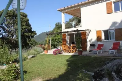 a white house with red chairs and a patio at Quenza-Alta Rocca in Quenza