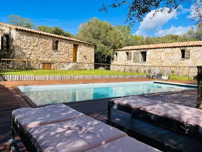 a swimming pool with two beds in front of a building at Les Bergeries de Petralonga in Sotta