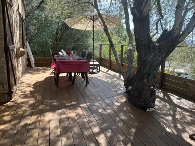 a wooden deck with a table and an umbrella at Les Bergeries de Petralonga in Sotta