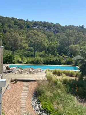 a swimming pool with two chairs next to a house at Santa Giulia Camara - Lecci Lodge in Lecci