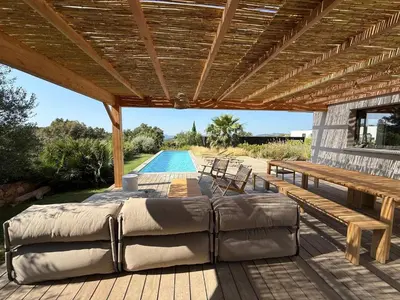 a wooden deck with chairs and a swimming pool at Santa Giulia Camara - Lecci Lodge in Lecci