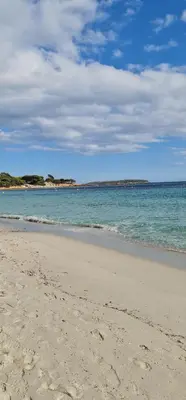 a patio with two chairs and a table and an umbrella at Studio pour 2 personnes à 700m de la plage de palombaggia in Porto-Vecchio