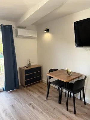 a dining room with a table and a tv at Studio 47 Cala Rossa Porto Vecchio in Lecci
