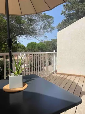 a table on a deck with an umbrella at Studio 47 Cala Rossa Porto Vecchio in Lecci