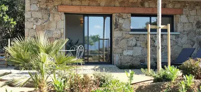a stone house with a glass door with a bench at Casa FIORI - 2 personnes - Vue mer in Pietrosella