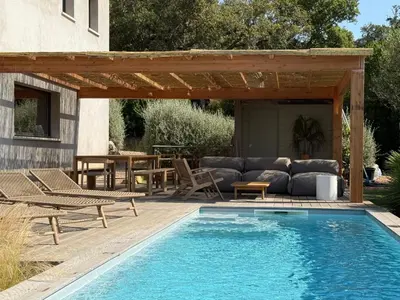 a swimming pool with a pergola next to a patio at Palombaggia Camara - Lecci Lodge in Lecci