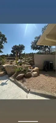 a garden with rocks and trees and an umbrella at Villa Mawie in Sotta