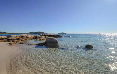 a sandy beach with rocks and the water at Cozy Home In Porto-Vecchio in Porto-Vecchio