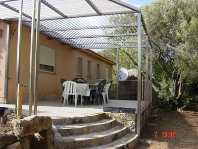 a patio with a table and chairs under a pergola at Tozzasim in Pianottoli-Caldarello