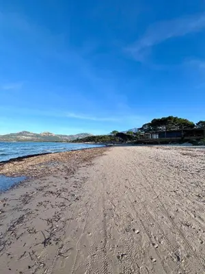 a beach with footprints in the sand and water at Typical Corsican Village House with Garden in Calenzana