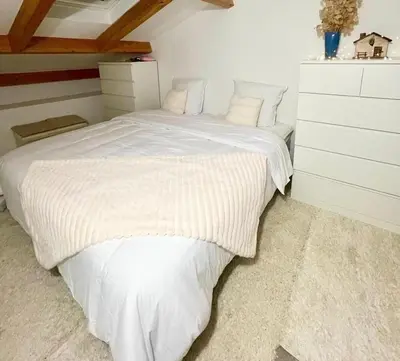 a bedroom with a white bed with a white dresser at Typical Corsican Village House with Garden in Calenzana