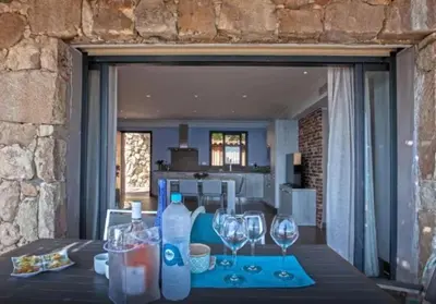 a table with two wine glasses and a kitchen at Appartement avec vue sur la mer à Olmeto in Olmeto