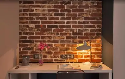 a desk in front of a brick wall with a lamp at Appartement avec vue sur la mer à Olmeto in Olmeto