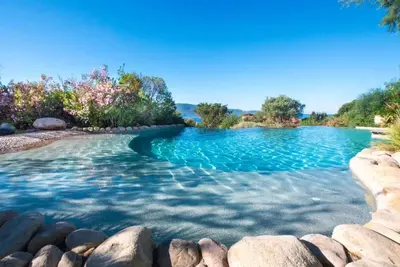 a swimming pool with rocks in the water at Charmante maison à Olmeto avec piscine partagée in Olmeto