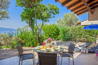 a patio with a table and chairs with a view of the ocean at Charmante maison à Olmeto avec piscine partagée in Olmeto