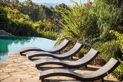 a group of benches sitting next to a pool at Charmante maison à Olmeto avec piscine partagée in Olmeto