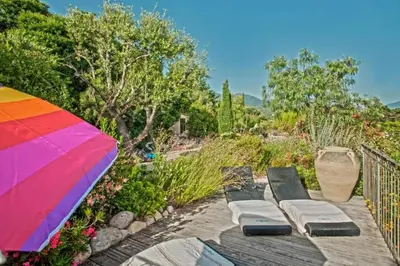 a colorful umbrella sitting on top of a wooden table at Charmante maison à Olmeto avec piscine partagée in Olmeto