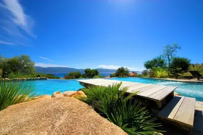 a large swimming pool with a wooden deck and a swimming pool at Charmante maison à Olmeto avec piscine partagée in Olmeto
