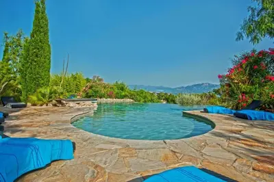 a swimming pool with blue loungers in a backyard at Charmante maison à Olmeto avec piscine partagée in Olmeto