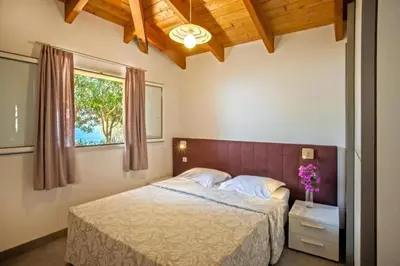 a bedroom with a bed and a window at Charmante Maison de Vacances à Olmeto avec Piscine in Olmeto