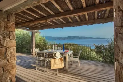 a patio with a table and chairs on a wooden deck at Villa moderne avec piscine privée à Olmeto - 95 m² in Olmeto
