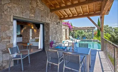 a patio with a table and chairs next to a pool at Villa moderne avec piscine privée à Olmeto - 95 m² in Olmeto