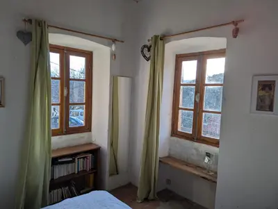 a bedroom with two windows and a bed and a book shelf at Maison de charme in Pioggiola