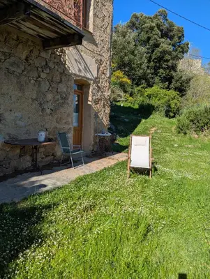 a house with a chair and a table in the grass at Maison de charme in Pioggiola