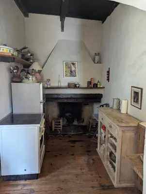 a kitchen with a white refrigerator and a fireplace at Maison de charme in Pioggiola