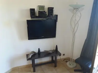 a living room with a tv and a table and a lamp at La Perle du Valinco #Familial#Balcon#Piscine#Mer in Propriano