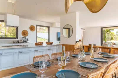 a dining room with a table and chairs and a kitchen at Villa U Pinu Di Pinarellu in Pinarellu