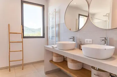 a bathroom with two sinks and a mirror at Villa U Pinu Di Pinarellu in Pinarellu
