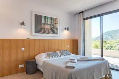 a bedroom with two beds and a large window at Villa U Pinu Di Pinarellu in Pinarellu