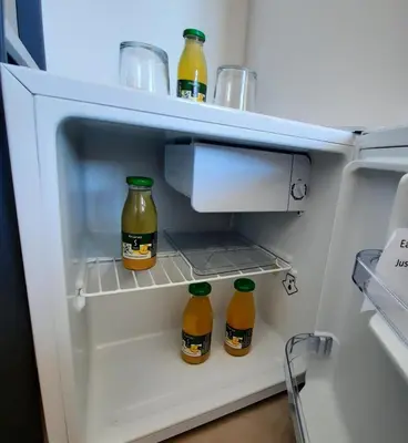 three bottles of orange juice in an open refrigerator at chambre face a la mer in Porticcio