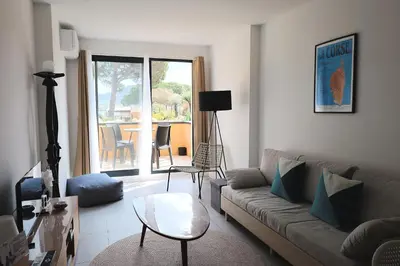 a dining room with a table and chairs and a living room at Casa di Daisy - T2 les pieds dans l'eau et piscine in Pianottoli-Caldarello