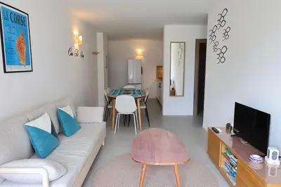 a living room with a white couch and a table at Casa di Daisy - T2 les pieds dans l'eau et piscine in Pianottoli-Caldarello