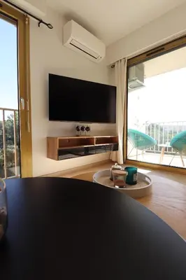 a living room with a flat screen tv and a table at Sublime Appartement avec Parking sur Ajaccio in Ajaccio