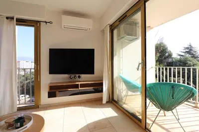 a living room with a television and a chair on a balcony at Sublime Appartement avec Parking sur Ajaccio in Ajaccio